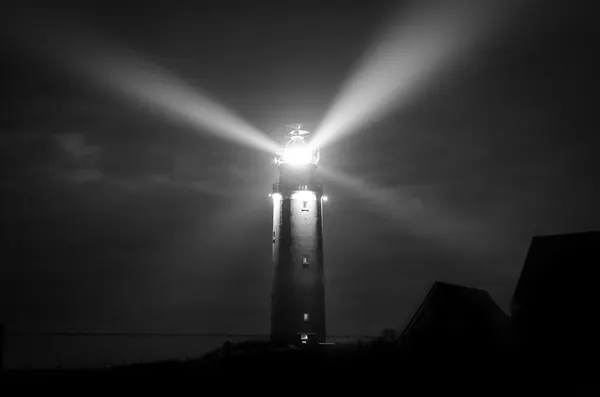 Faro de noche, con los haces de luz cruzando el cielo
