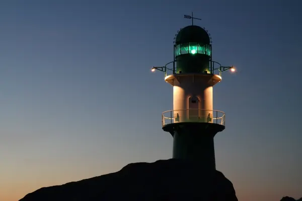Faro con la luz verde encendida al anochecer
